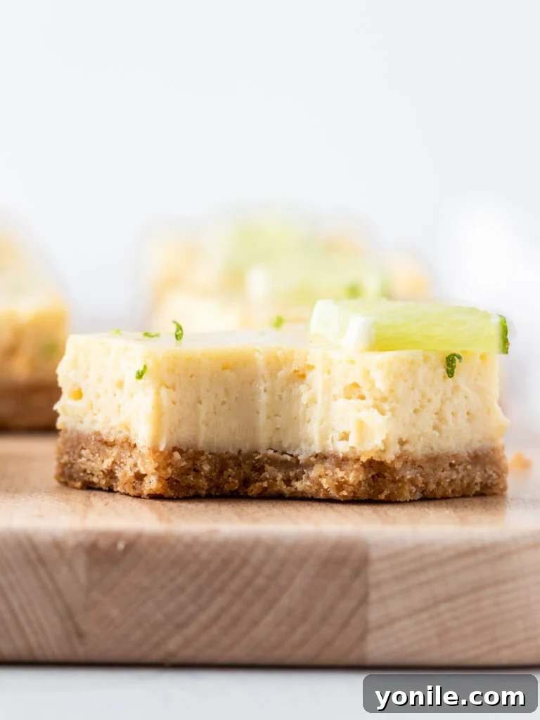 A close-up shot of a Key Lime Pie bar with a bite taken out, highlighting its creamy texture and the contrast with the golden crust, ready to be enjoyed.