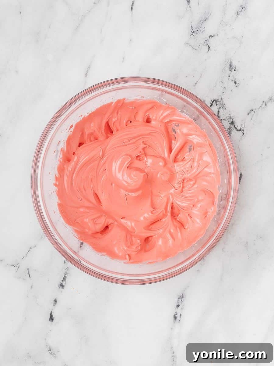 A vibrant red meringue, fluffy and firm, demonstrating stiff peaks, ready to be folded into the dry ingredients for macaron batter.