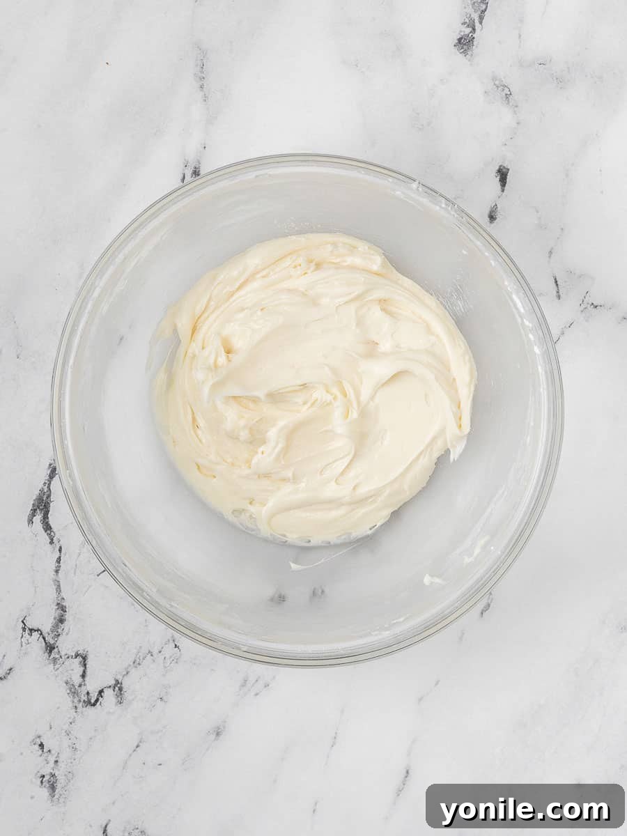 A bowl of rich, velvety cream cheese filling, smooth and perfectly whipped, ready to be piped into the red velvet macaron shells.