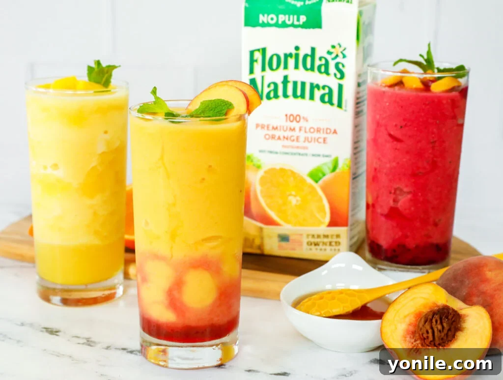 Three different vibrant orange slushies in elegant glasses, displayed on a counter alongside a carton of Florida's Natural orange juice.