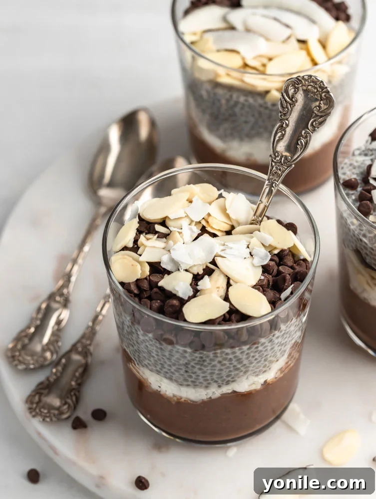 almond joy chia pudding in a cup garnished with some nuts and chocolate chips