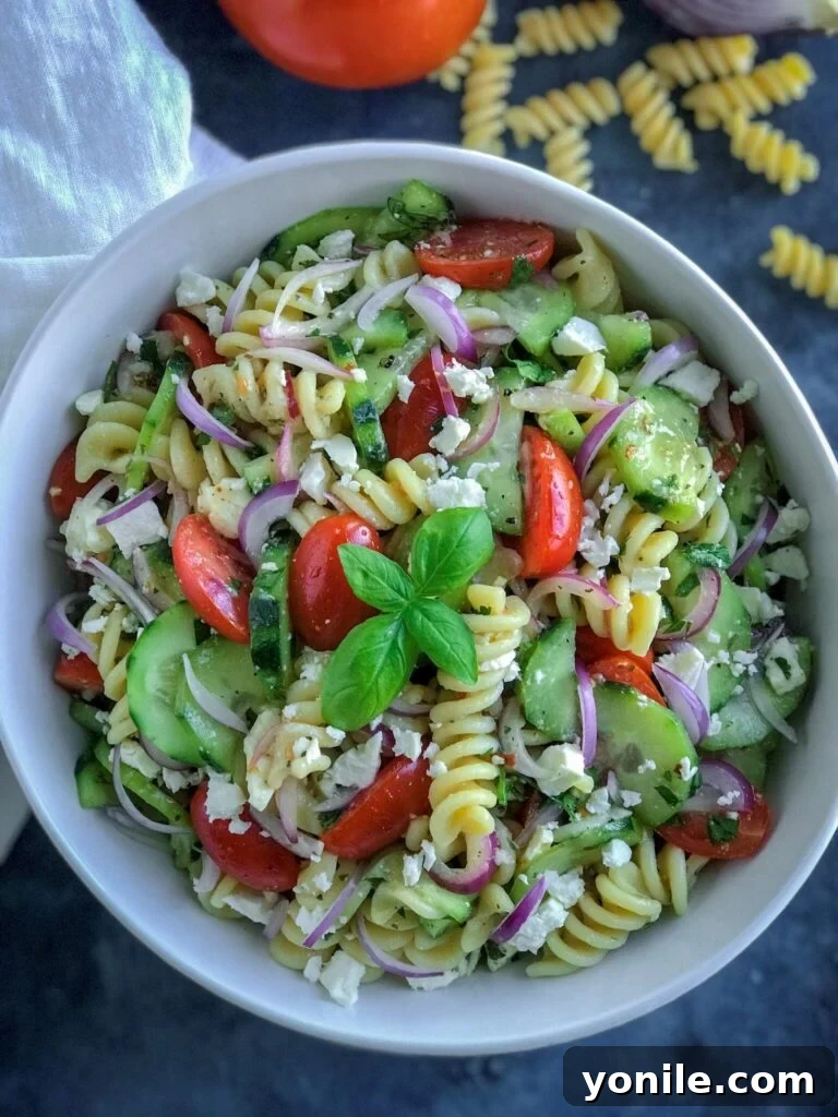 A large bowl of delicious Greek Pasta Salad, garnished with fresh herbs, ready for serving at a party or family meal