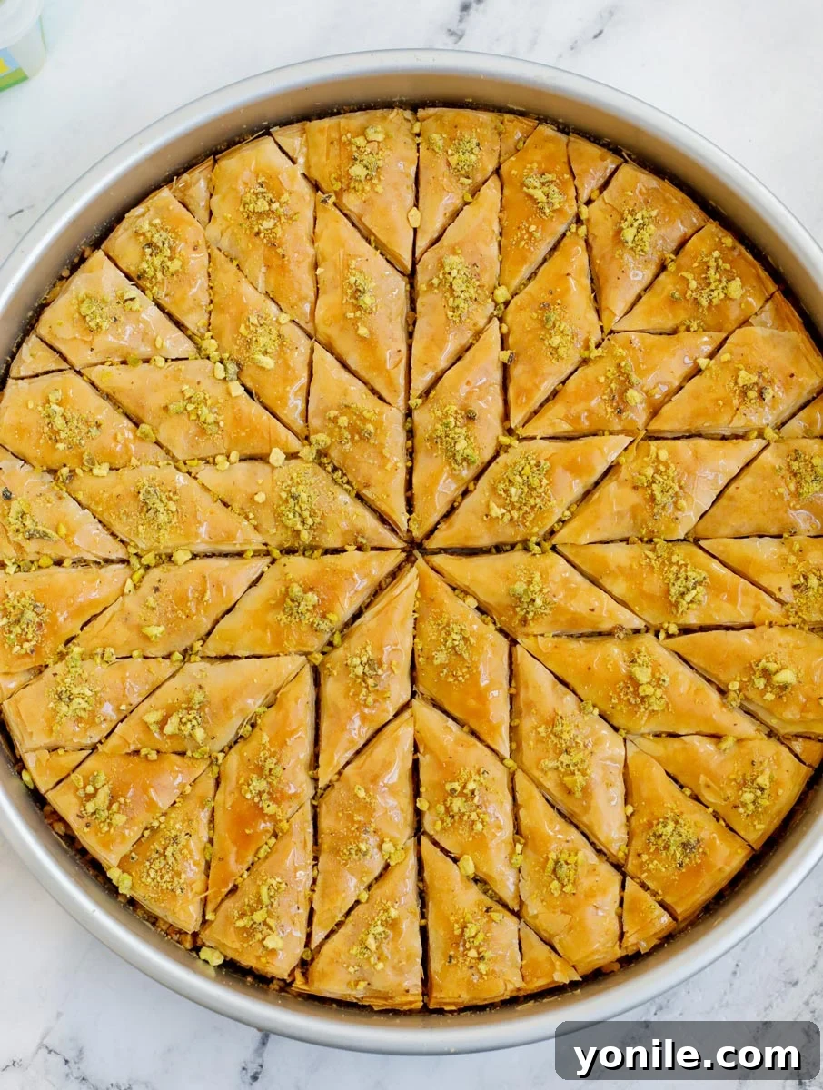 A close-up shot of baked walnut baklava, glistening with simple syrup, cut into elegant diamond shapes and ready to serve.