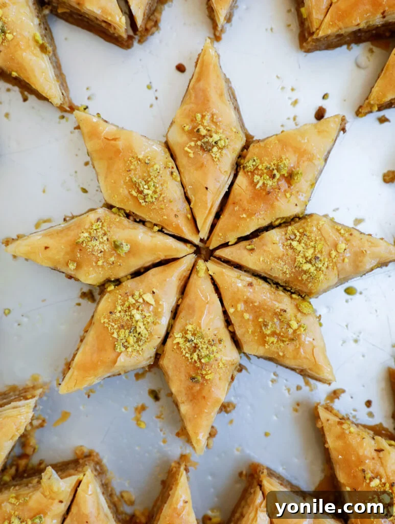 An artfully cut piece of walnut baklava, shaped like a star, glistening with syrup and adorned with finely ground pistachios.