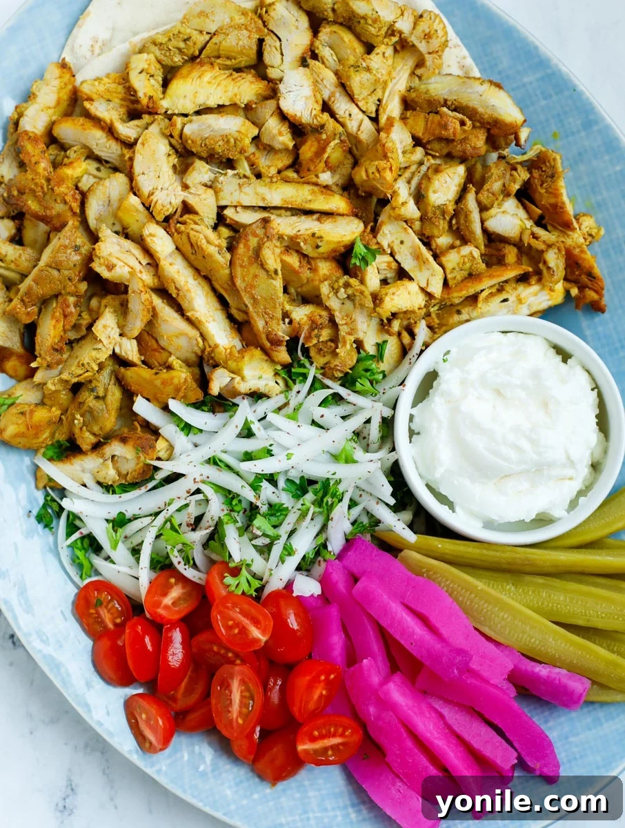 A platter of chicken shawarma with dip and sides.