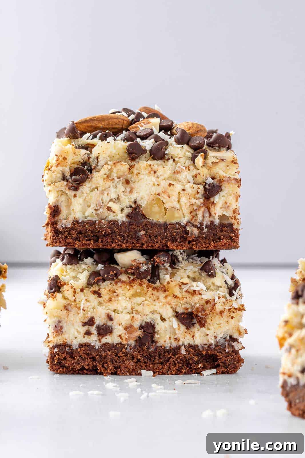 Two perfectly stacked Almond Joy cheesecake bars, showcasing their distinct layers and inviting texture.
