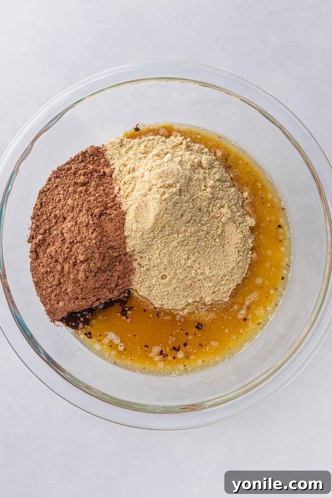Crushed graham cracker crumbs mixed with cocoa powder in a bowl, ready for butter.