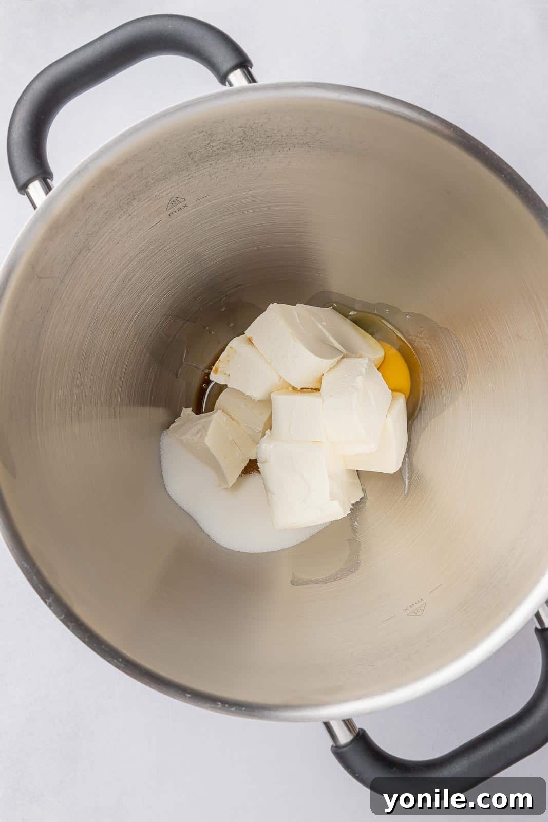 Cream cheese and egg being beaten together in a mixing bowl for the cheesecake filling.