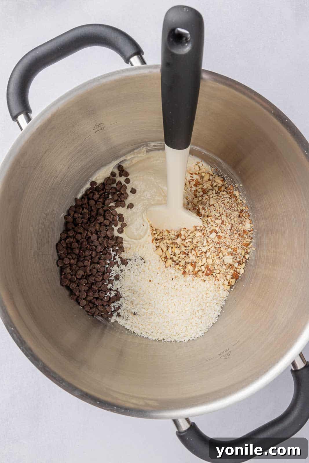 The Almond Joy cheesecake filling, rich with coconut, chocolate chips, and almonds, poured over the crust in the baking pan.