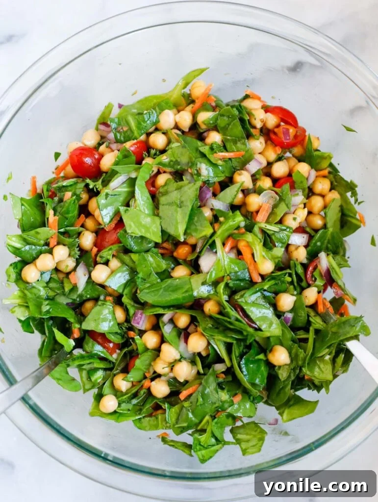 A vibrant spinach chickpea salad, freshly tossed and ready to be served, showcasing the mixed ingredients.
