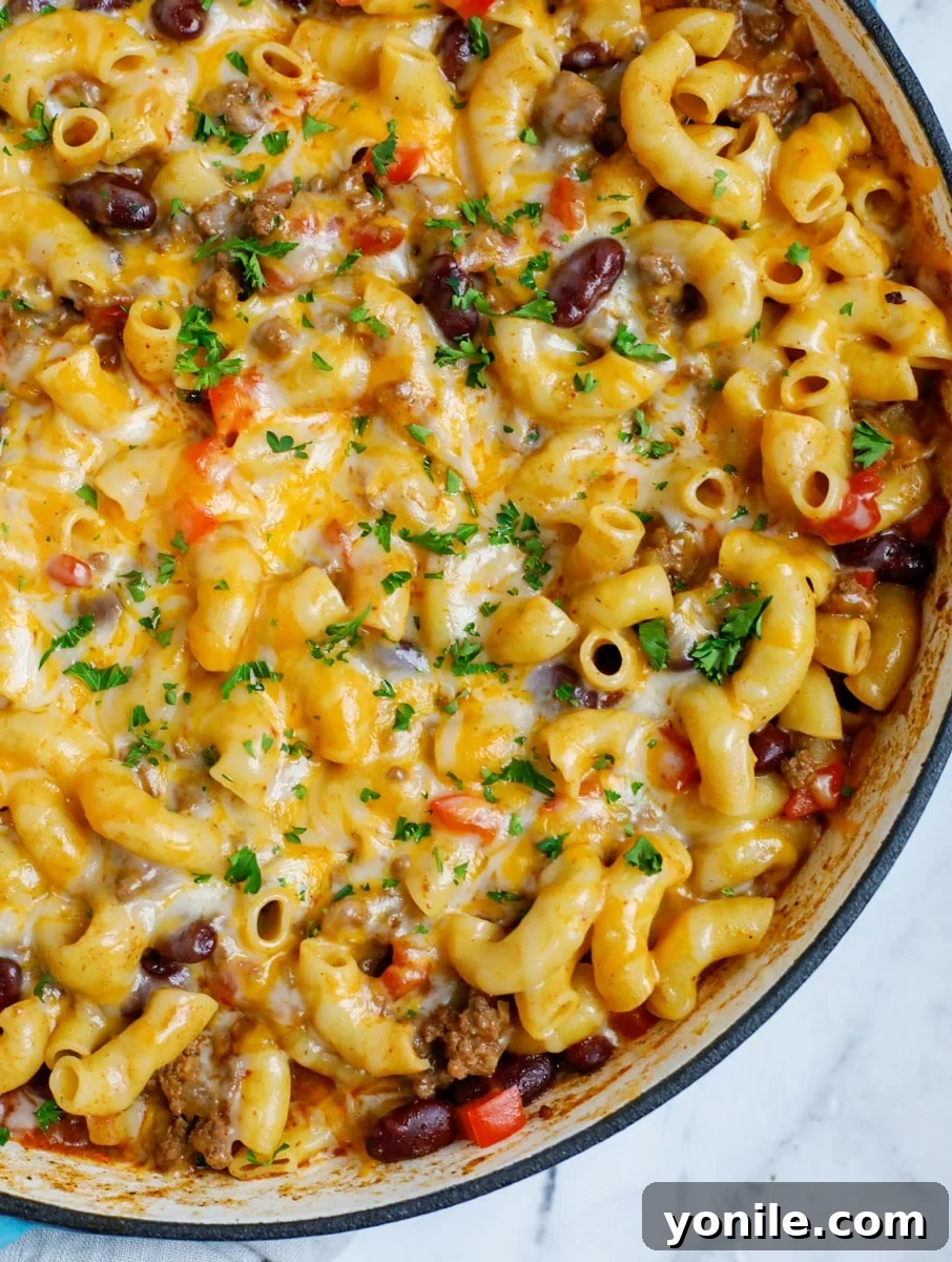 Close up of a bubbling pot of chili mac and cheese, showcasing the rich sauce and melted cheese.