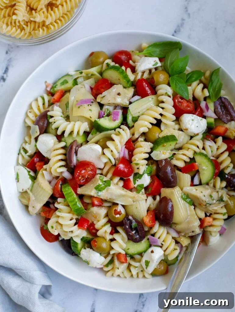 Vibrant Mediterranean Pasta Medley 2 A vibrant Mediterranean pasta salad in a large serving bowl, garnished with fresh herbs and lemon wedges.