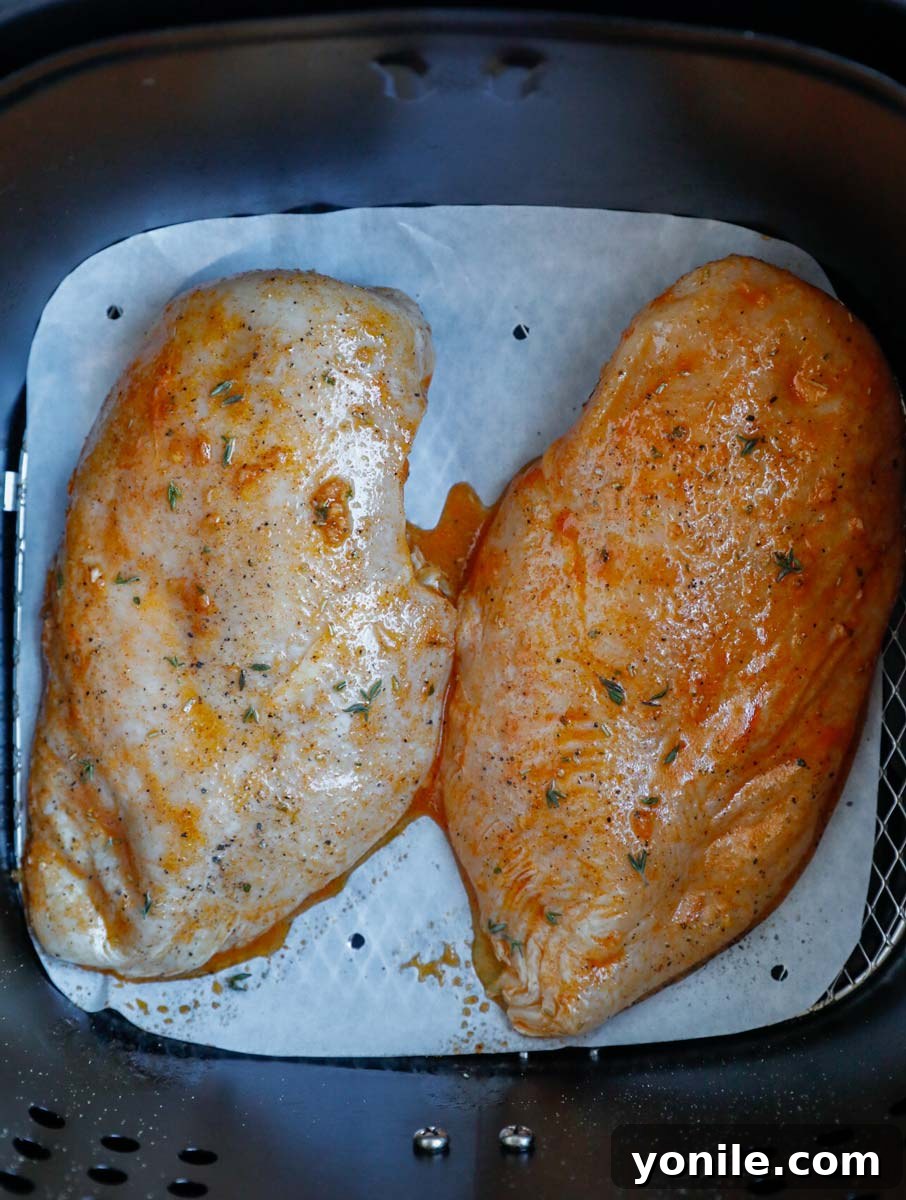 Crispy Rosemary Air Fryer Chicken 6 Two chicken breasts in an air fryer basket.
