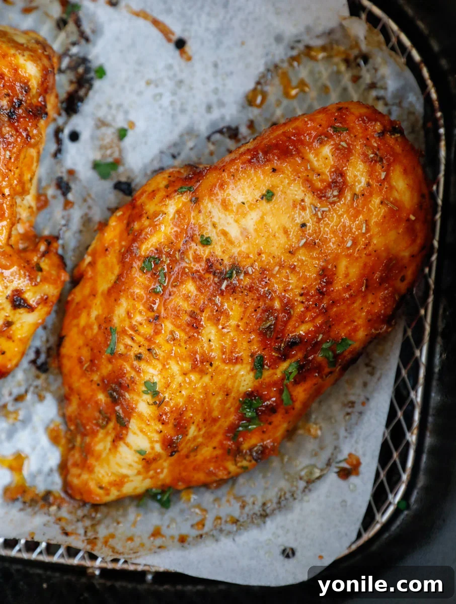 Crispy Rosemary Air Fryer Chicken 7 air fried chicken breasts in an air fryer basket.