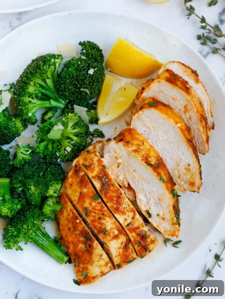 Crispy Rosemary Air Fryer Chicken 8 A plate of sliced air fryer rosemary chicken breast beside broccoli.