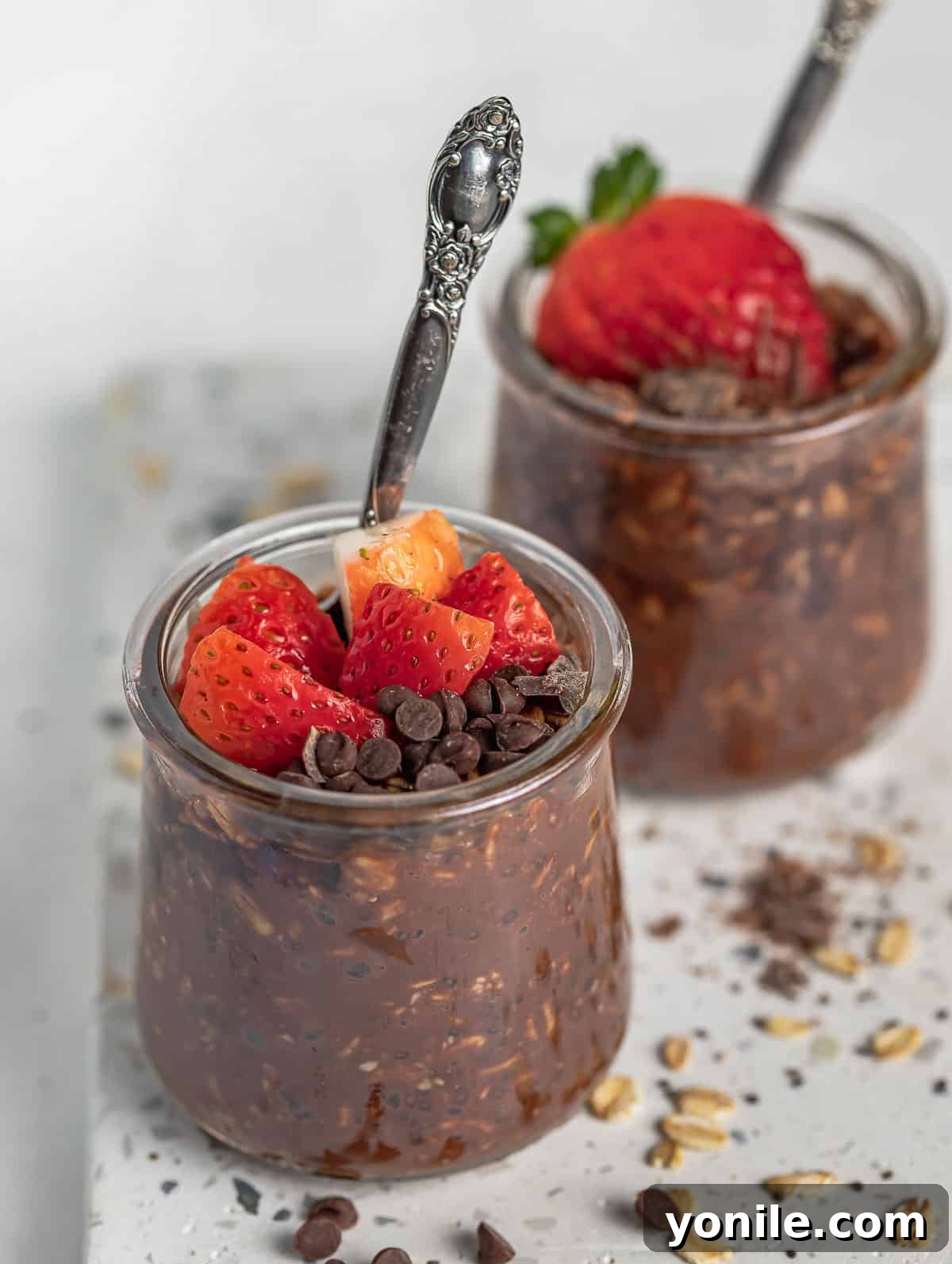 two cups of chocolate overnight oats topped with strawberry and chocolate chips