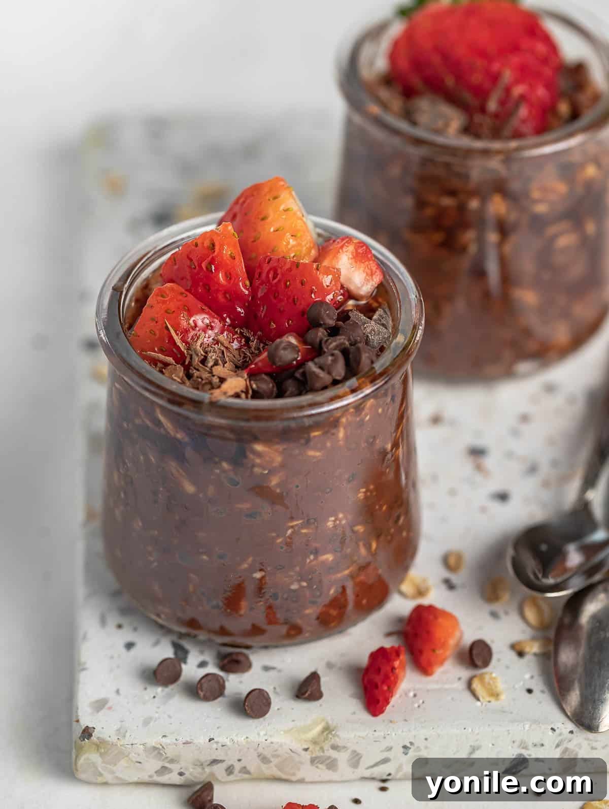 two cups of chocolate overnight oats topped with strawberry and chocolate chips