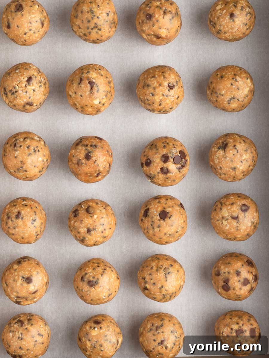 Effortless Energy Bites 6 Freshly rolled No-Bake Energy Balls neatly laid out on a sheet pan lined with parchment paper, ready for chilling.