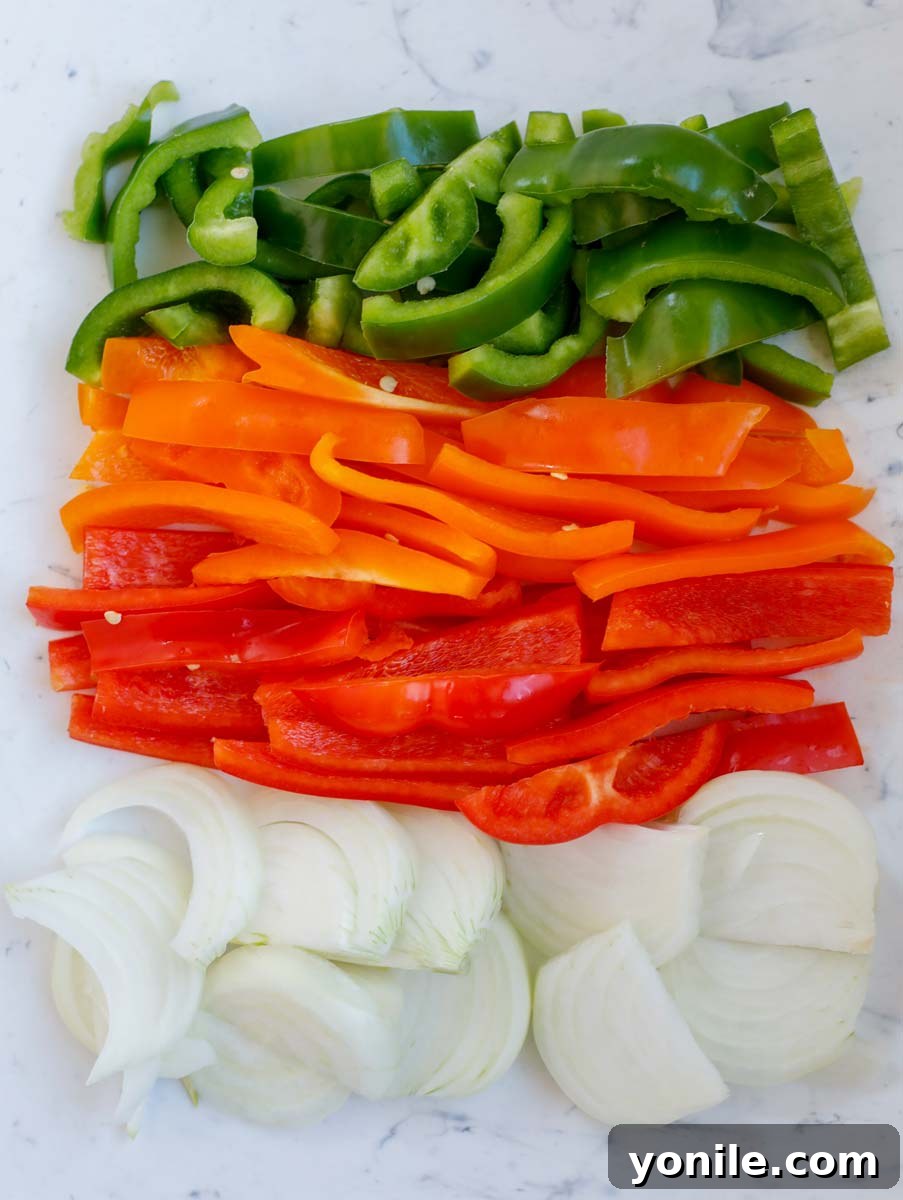 Freshly sliced green, red, and orange bell peppers, alongside chopped onions.