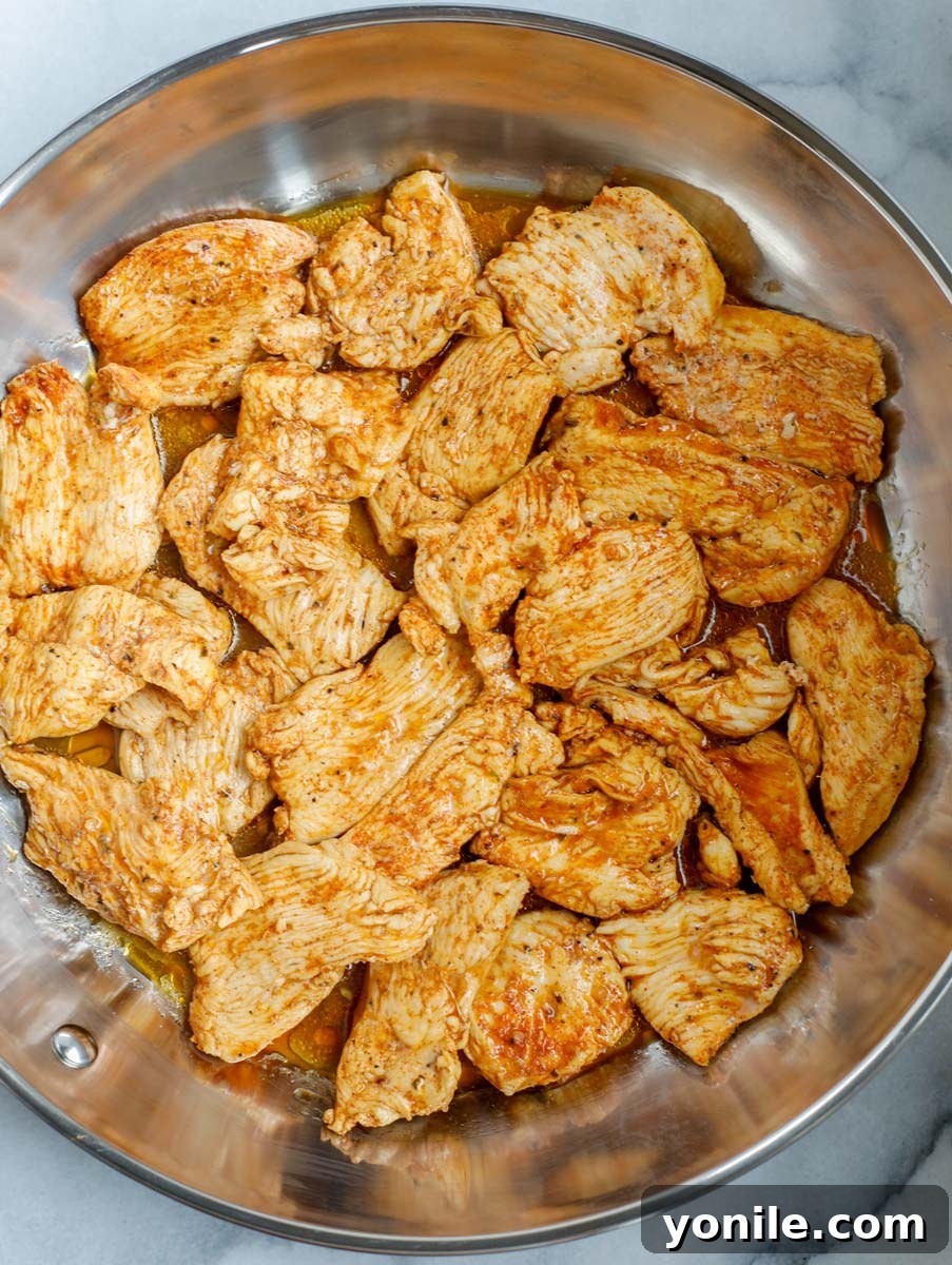 Chicken searing in a hot non-stick skillet.