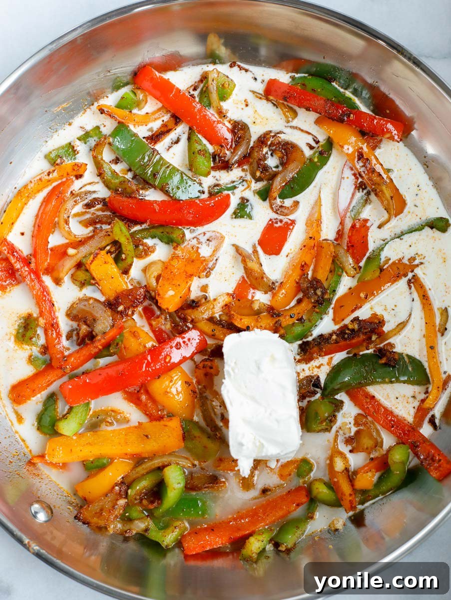 Heavy cream and brick cream cheese being added to the skillet with vegetables.