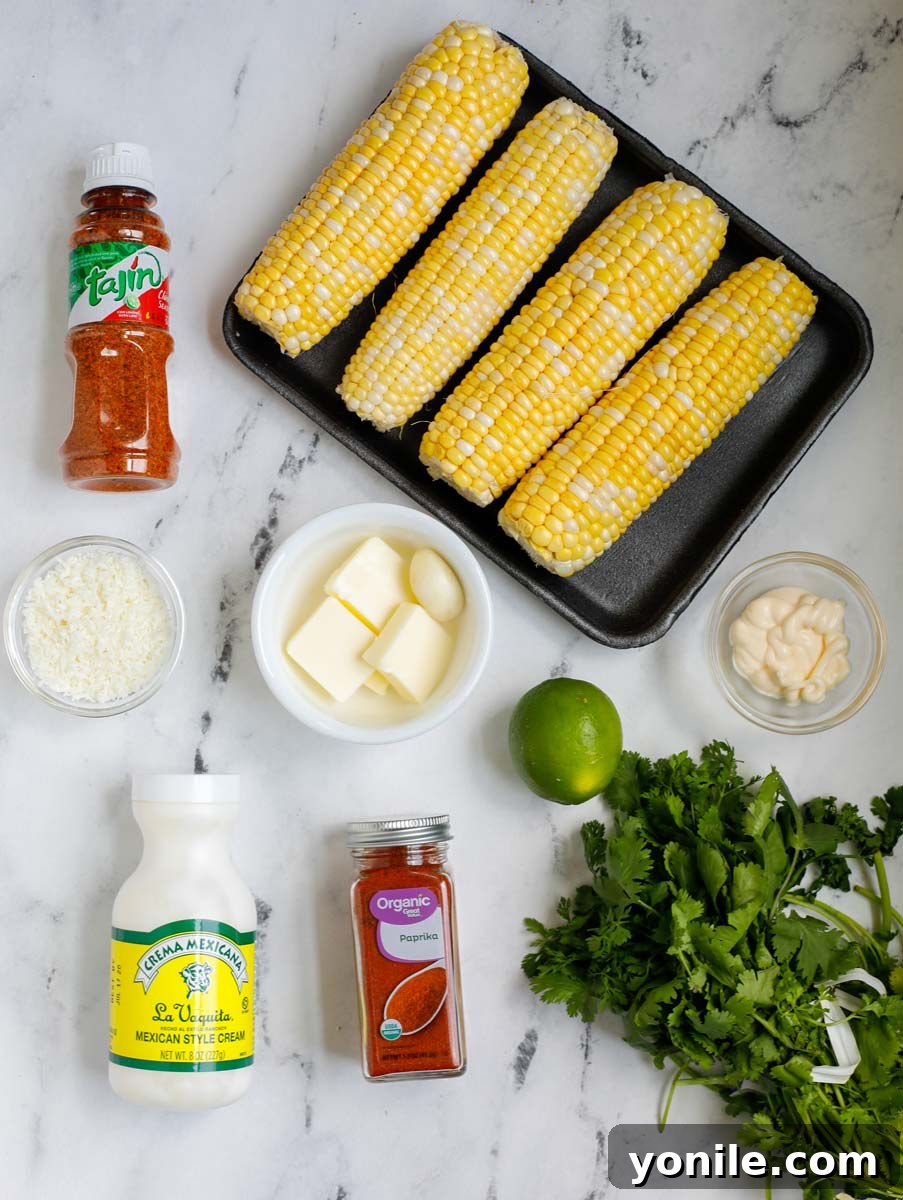 Overhead view of fresh ingredients required to make Mexican street corn, including corn, butter, cheese, cilantro, and lime.