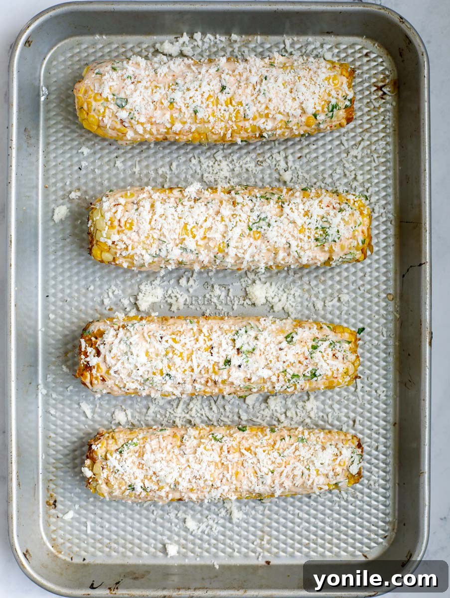 Mexican street corn topped with cotija cheese, ready for more garnish.