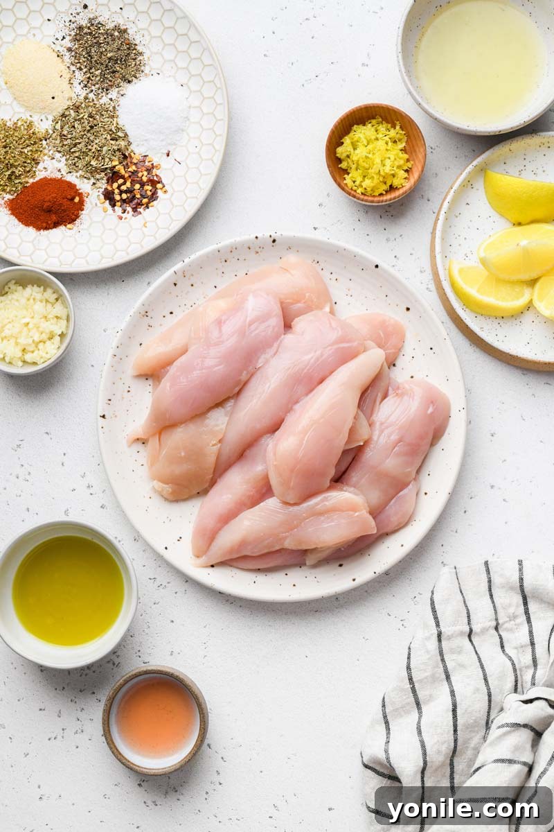 All the fresh ingredients for Greek chicken skewers, including chicken, lemons, herbs, and spices, laid out on a kitchen counter