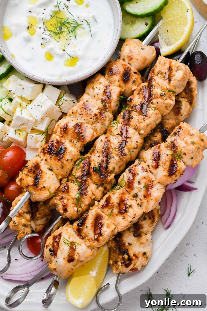 Close-up detailed shot of tender, charred Greek chicken skewers resting on a serving plate