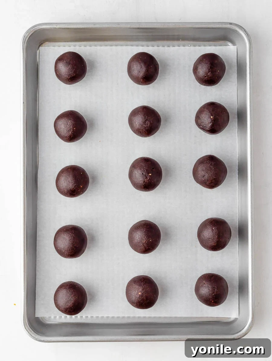 Freshly rolled brownie energy bites laid out on a sheet pan for chilling.
