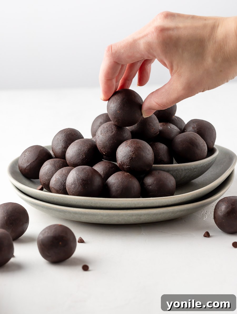 Fingers holding a piece of a brownie energy bite, showcasing its ready-to-eat appeal.