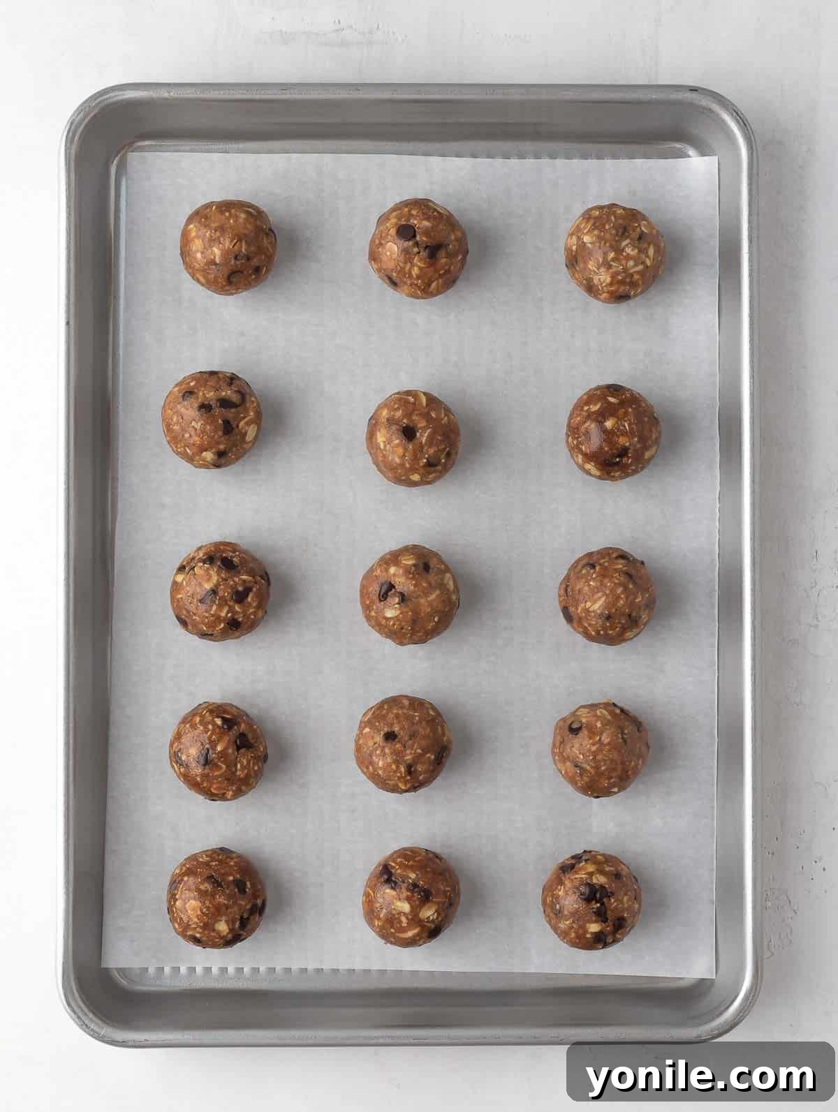 Freshly rolled chocolate peanut butter protein balls neatly arranged on a tray lined with parchment paper, ready for chilling.