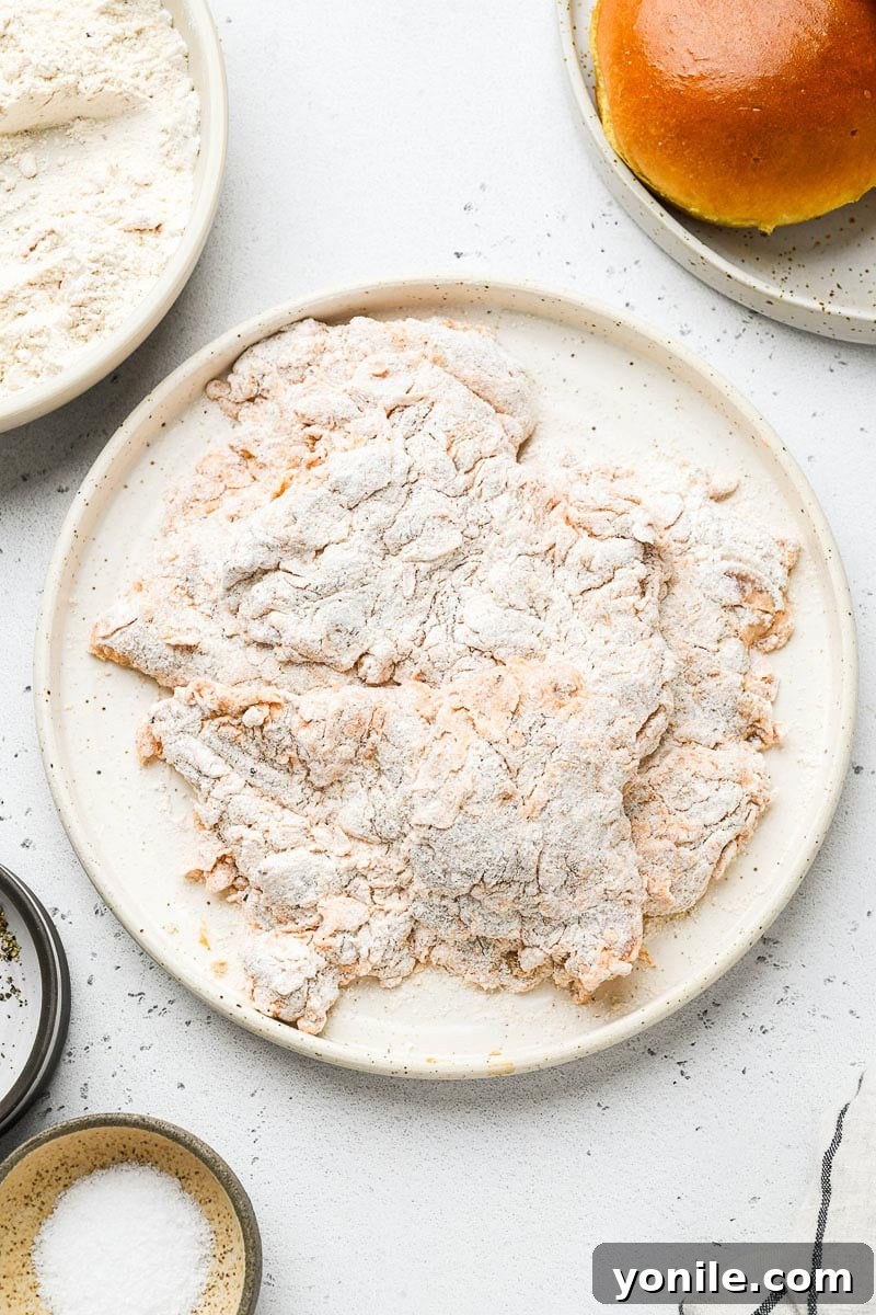 Chicken thighs coated evenly in flour mixture, ready for frying.