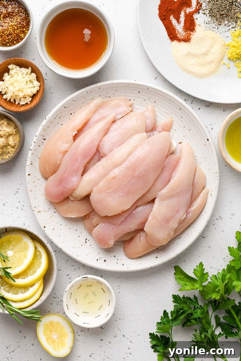 A collection of ingredients laid out on a counter, including chicken tenders, various spices, honey, mustard, and lemon, all ready to be assembled for grilled honey mustard chicken.