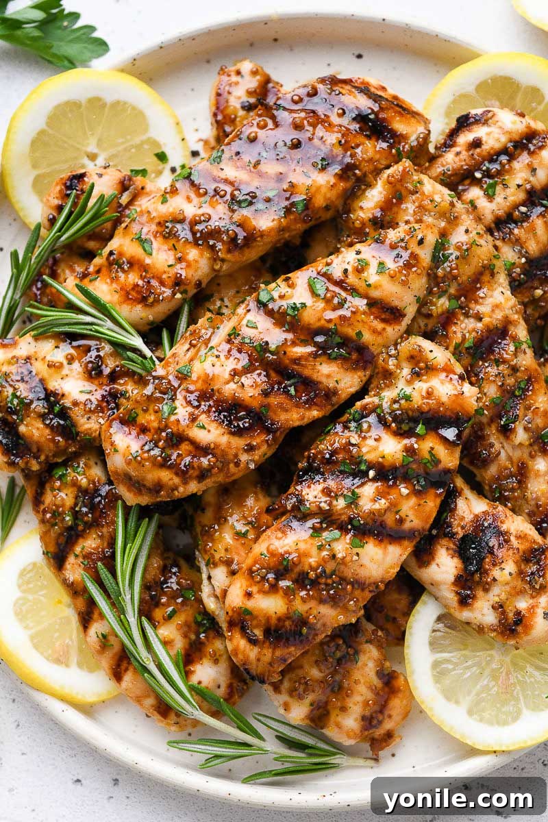 Close up of a plate of perfectly grilled honey mustard chicken, showcasing its golden-brown exterior and juicy texture.