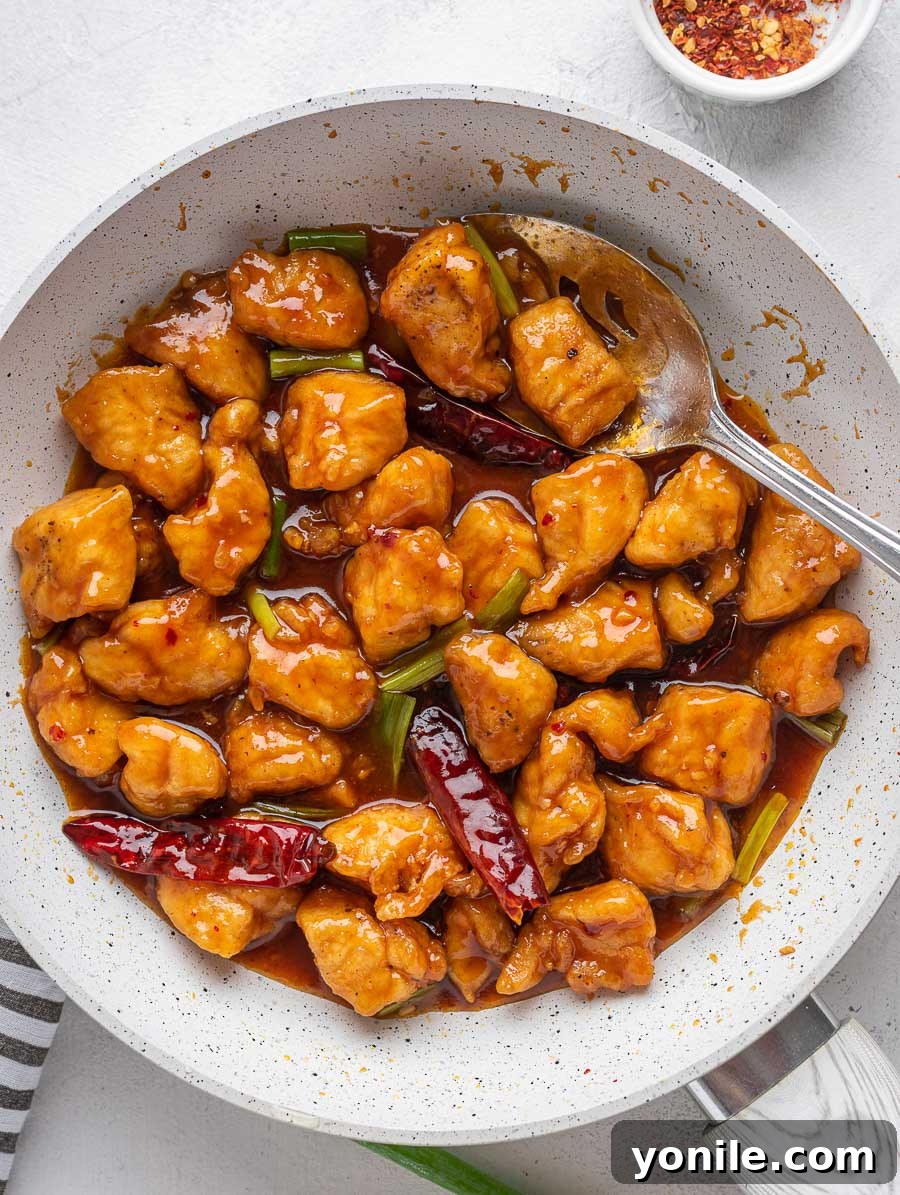 No-Fuss Mongolian Chicken 8 Mongolian chicken simmering in a skillet with a serving spoon, ready to be served