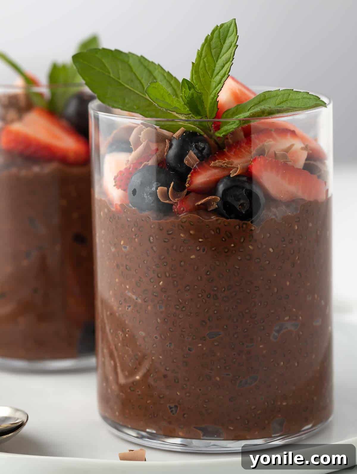 A close-up shot of the rich chocolate chia pudding, generously topped with an assortment of vibrant berries, showcasing its creamy texture.