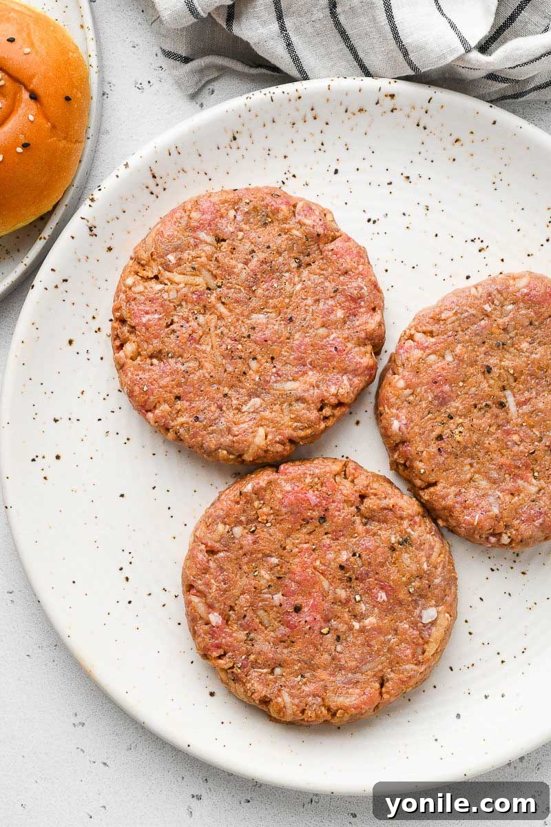 Gourmet Burgers at Home 5 Three perfectly formed raw beef patties, ready for grilling, arranged neatly on a plate.
