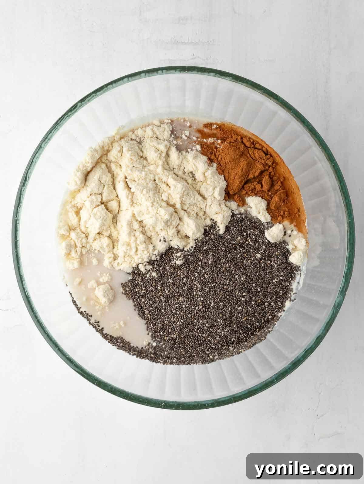 All the dry and wet ingredients for the cinnamon apple Overnight Chia pudding in a bowl, before being mixed together.