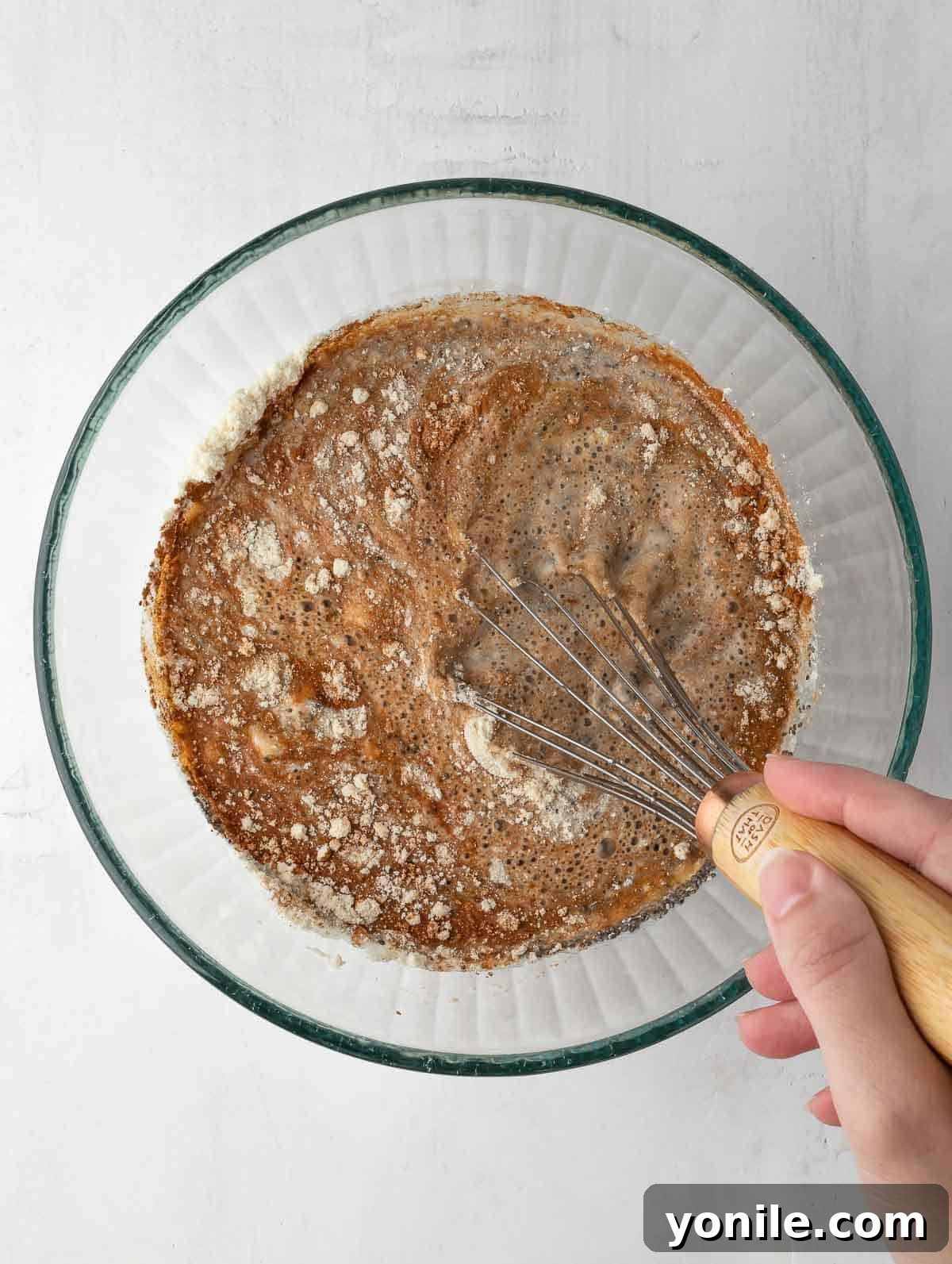 A whisk vigorously mixing all the ingredients together in a bowl, ensuring a smooth and lump-free chia pudding base.