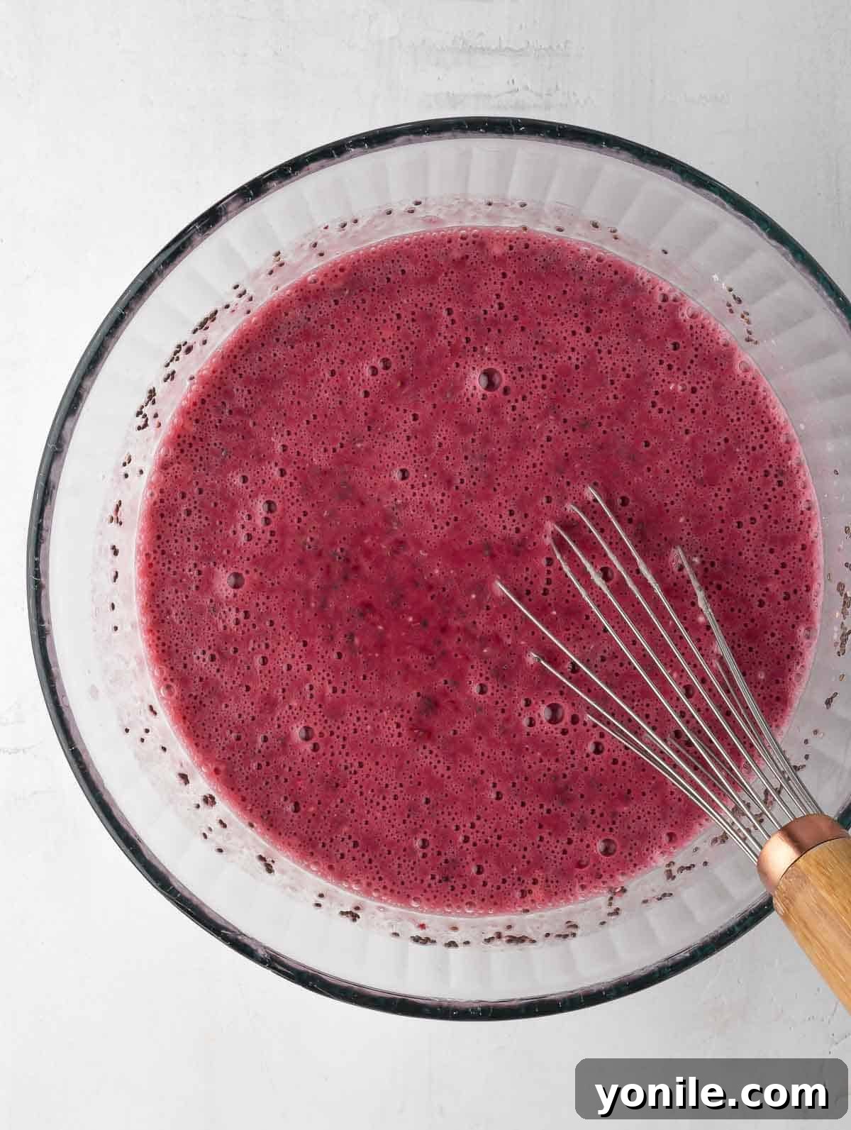 All ingredients for Raspberry Protein Chia Pudding thoroughly mixed in a bowl with a whisk, showing a smooth consistency.
