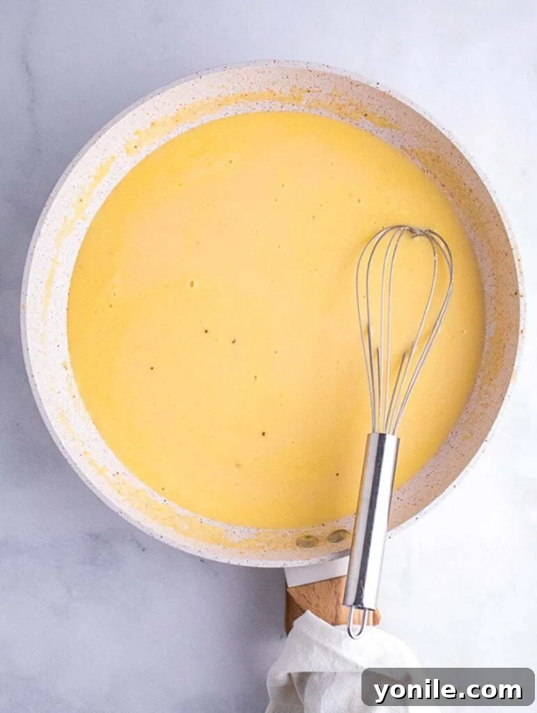 Top down shot of a creamy roux being prepared in a skillet, bubbling gently.