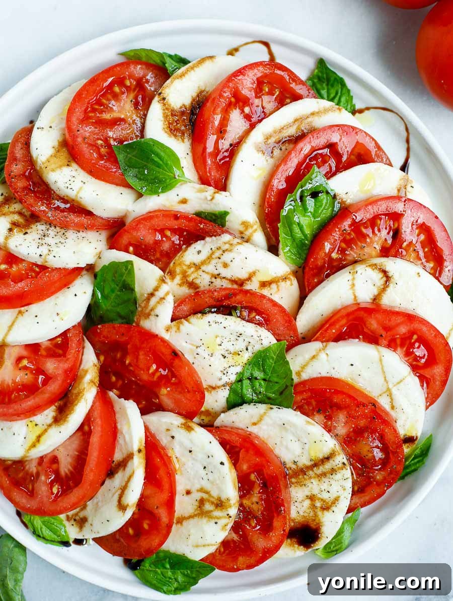 close up shot of the dressed caprese salad dish with balsamic glaze and olive oil glistening on the fresh ingredients