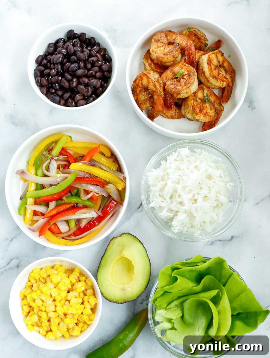 An overhead shot of all the colorful and fresh ingredients for a Healthy Chipotle Shrimp Bowl before assembly.