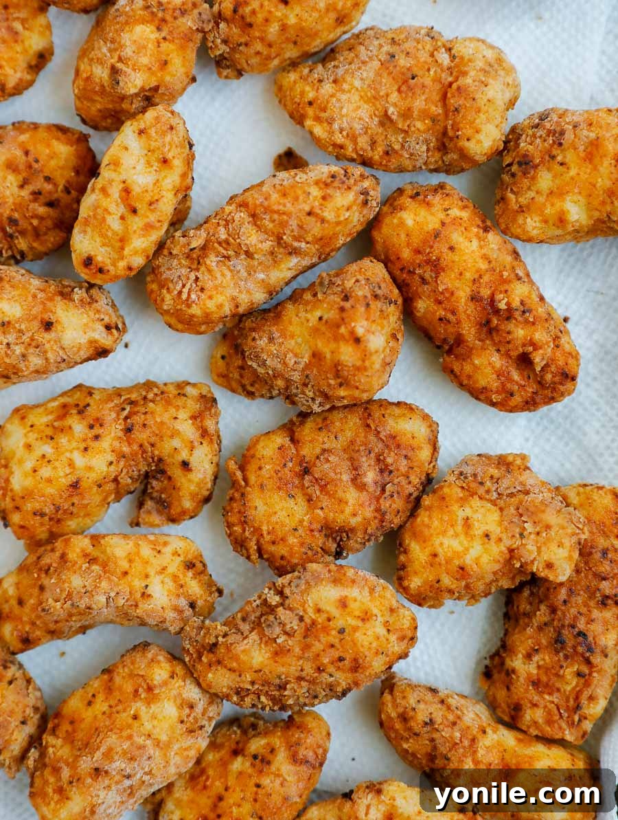 Addictive Chicken Crisps 6 Freshly fried crispy chicken bites resting on a paper towel-lined sheet pan to drain excess oil.