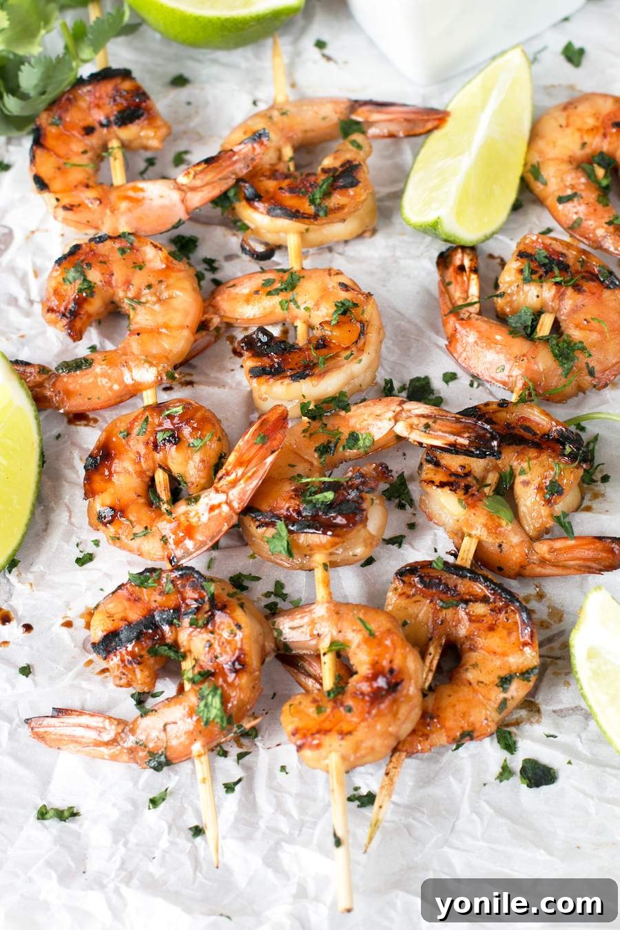 Agave Cilantro Shrimp Skewers with dipping sauce and lime on parchment paper. Agave Cilantro Shrimp Skewers on parchment paper with lime and cilantro