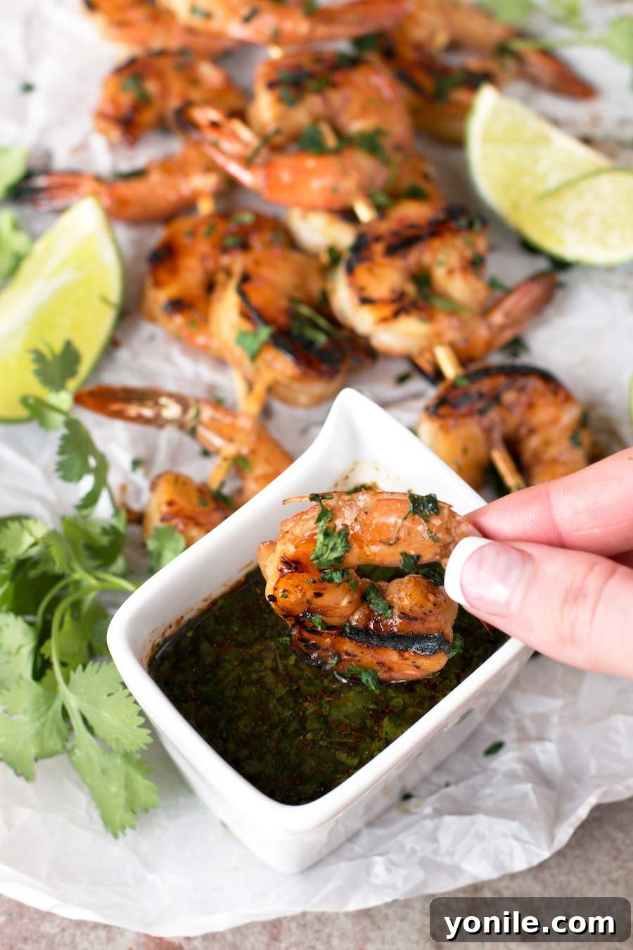 Agave-Glazed Cilantro Shrimp Skewers 2 Someone dipping Agave Cilantro Shrimp Skewers into spicy dipping sauce.