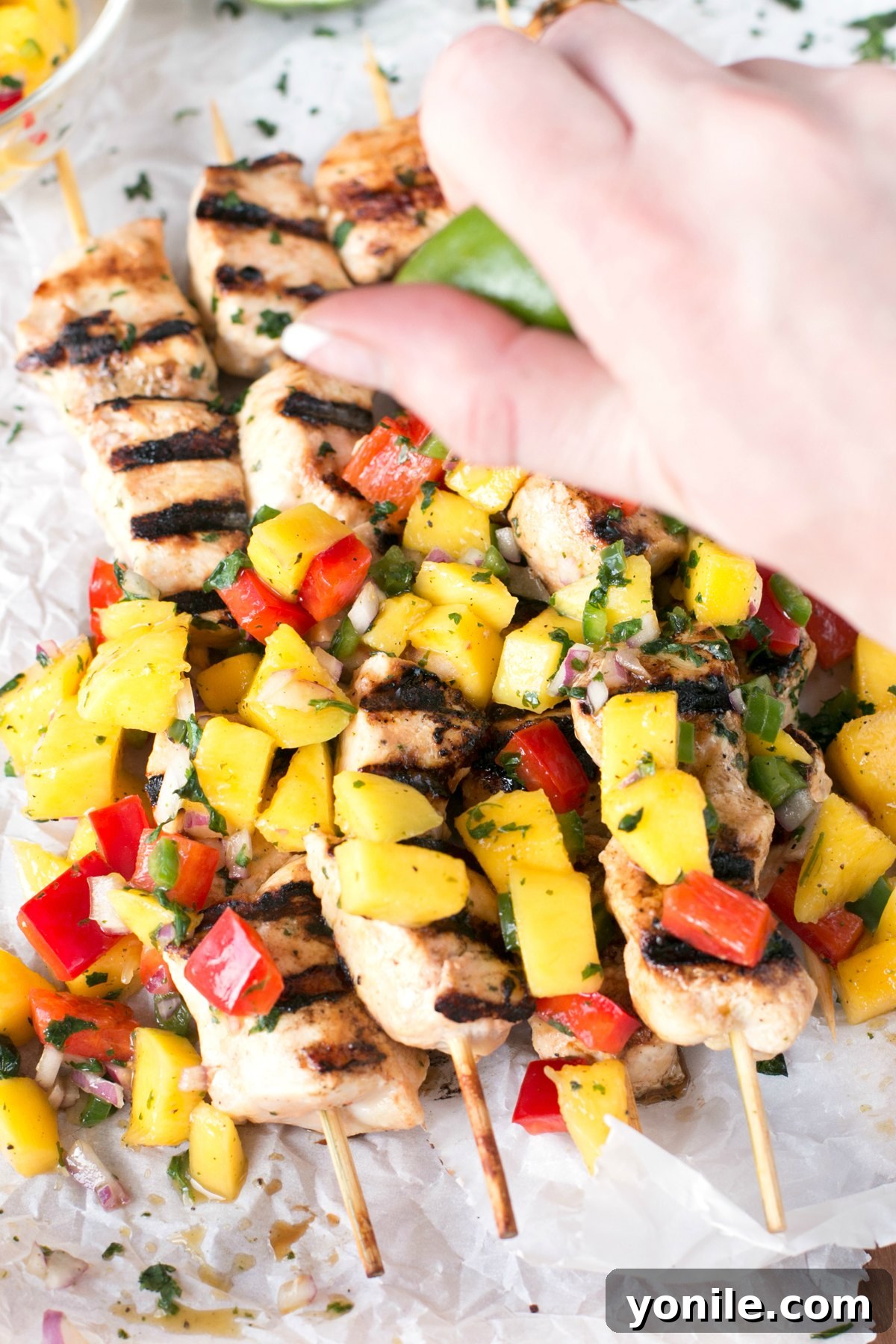 Mango chicken topped with mango salsa and a hand squeezing fresh lime on top