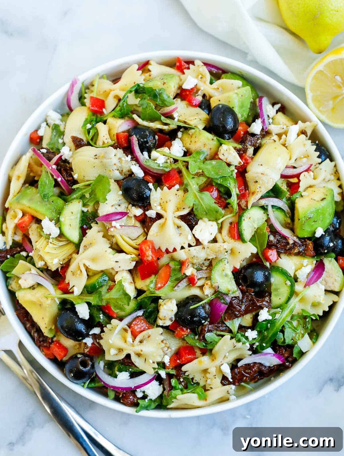 Zesty Mediterranean Pasta Salad 8 lemon herb Mediterranean salad served in a white bowl, with a side of lemon