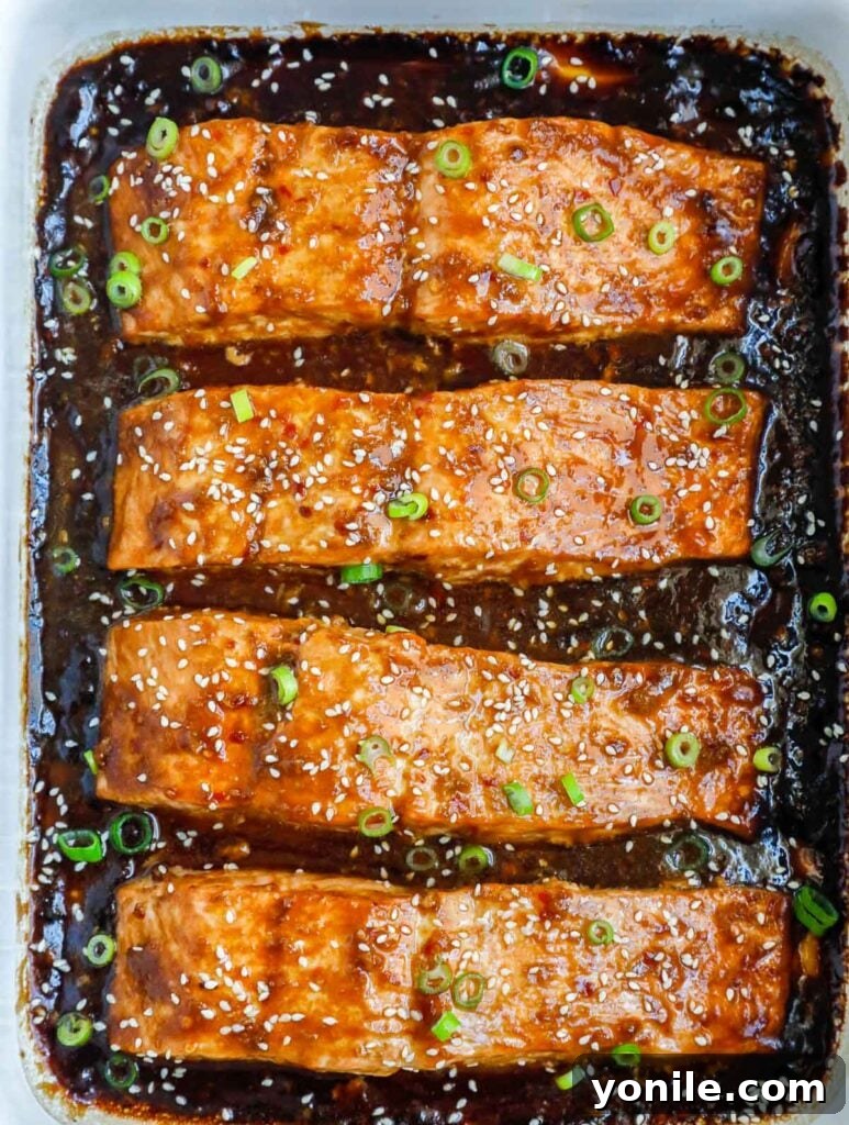 Golden Teriyaki Salmon Bake 6 Freshly baked teriyaki salmon, beautifully glazed and garnished with green onions and sesame seeds, presented in a baking dish.